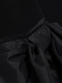Detail of the matte knit and gathered taffeta bow on the SIMKHAI Tedda Mini Dress in Black.