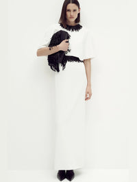 Styled full-length look of the SIMKHAI Vantrel Short Sleeve Gown in Ivory with a beaded fringe clutch.
