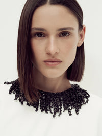 Portrait detail of the black beaded fringe neckline on the SIMKHAI Vantrel Short Sleeve Gown in Ivory.