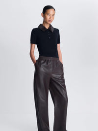 Model wearing the SIMKHAI Vayla Wool Cashmere Polo in Black Chocolate Multi with brown leather pants.