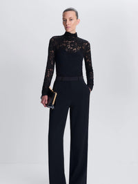 Full front view of the SIMKHAI Zurie Lace Bodysuit in Black tucked into wide-leg black trousers.