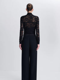 Back view of the SIMKHAI Zurie Lace Bodysuit in Black showing sheer lace across the shoulders and sleeves.