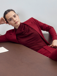 Model wearing the Cowl Neck Knit Shell in garnet by SMYTHE, styled on a taupe table