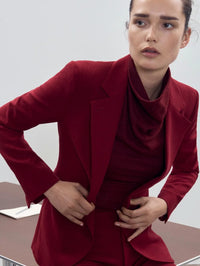 Editorial view of the SMYTHE Cowl Neck Knit Shell in Garnet layered under a red tailored blazer