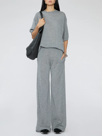 Front view of the Wide Leg Pants in grey by SPRWMN, styled with a matching grey tee and black shoulder bag