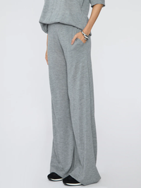 Side view of the grey Wide Leg Pants by SPRWMN with hand in pocket, styled with black and white sneakers