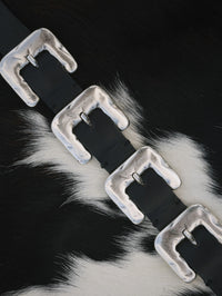 Detail of the Streets Ahead Multi Silver Buckle Belt in black leather laid on cowhide
