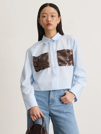 Front view of the Tanya Taylor Largaux Top in Oxford Blue with sequined front pockets, worn with jeans.