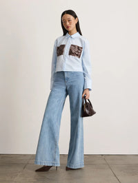 Angled full length view of the Tanya Taylor Largaux Top in Oxford Blue with cuffed long sleeves.