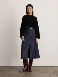 Full length front view of the black Tanya Taylor Marina Cashmere Sweater tucked into a denim midi skirt.