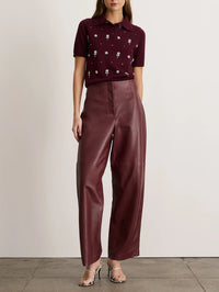 Front view of the Tanya Taylor Weston Leather Pant in Mahogany, worn high-waisted with a knit polo.