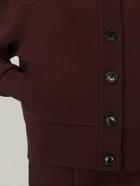 Close-up of the ribbed placket, buttons and welt pocket on the Varley Olwen Sweater in Deep Mahogany