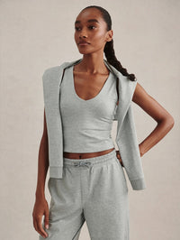 Styled front view of the Varley Ruby Cropped Tank in Blue Green Marl with a sweatshirt tied over the shoulders