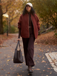 Full-length outdoor view of the Varley Serina Reversible Quilt Jacket in Cherry Mahogany, sherpa side out