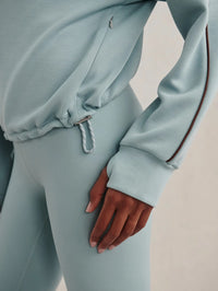 Detail of the zip pocket, drawcord hem and thumbhole on the Varley Sian Half-Zip Sweat in Tourmaline
