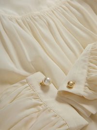 Close-up of the gathered crepe and pearl and gold cuff links on the Veronica Beard Brooks Blouse in Dove White.