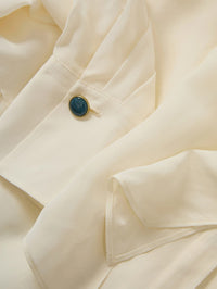 Close-up of the cabochon cuff button on the Veronica Beard Darlis Scarf-Neck Blouse in Dove White.