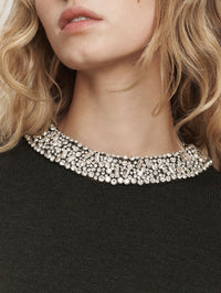 Detail of the crystal crew neckline on the Veronica Beard Daro Embellished Sweater in Green Shadow.