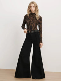 Full-length front view of the Veronica Beard Wyeth Zebra Turtleneck Top in Ochre/Black with black wide-leg jeans.