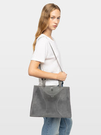 Model carrying the Zadig & Voltaire Jack Suede Bag in Road grey crossbody with a white tee and denim.